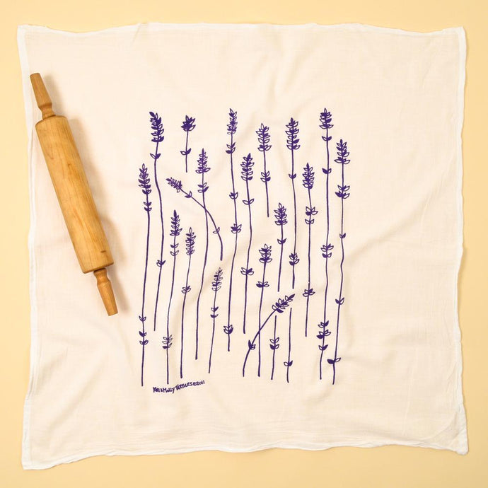 Photograph of a dishtowel with purple lavender sprigs printed on it.