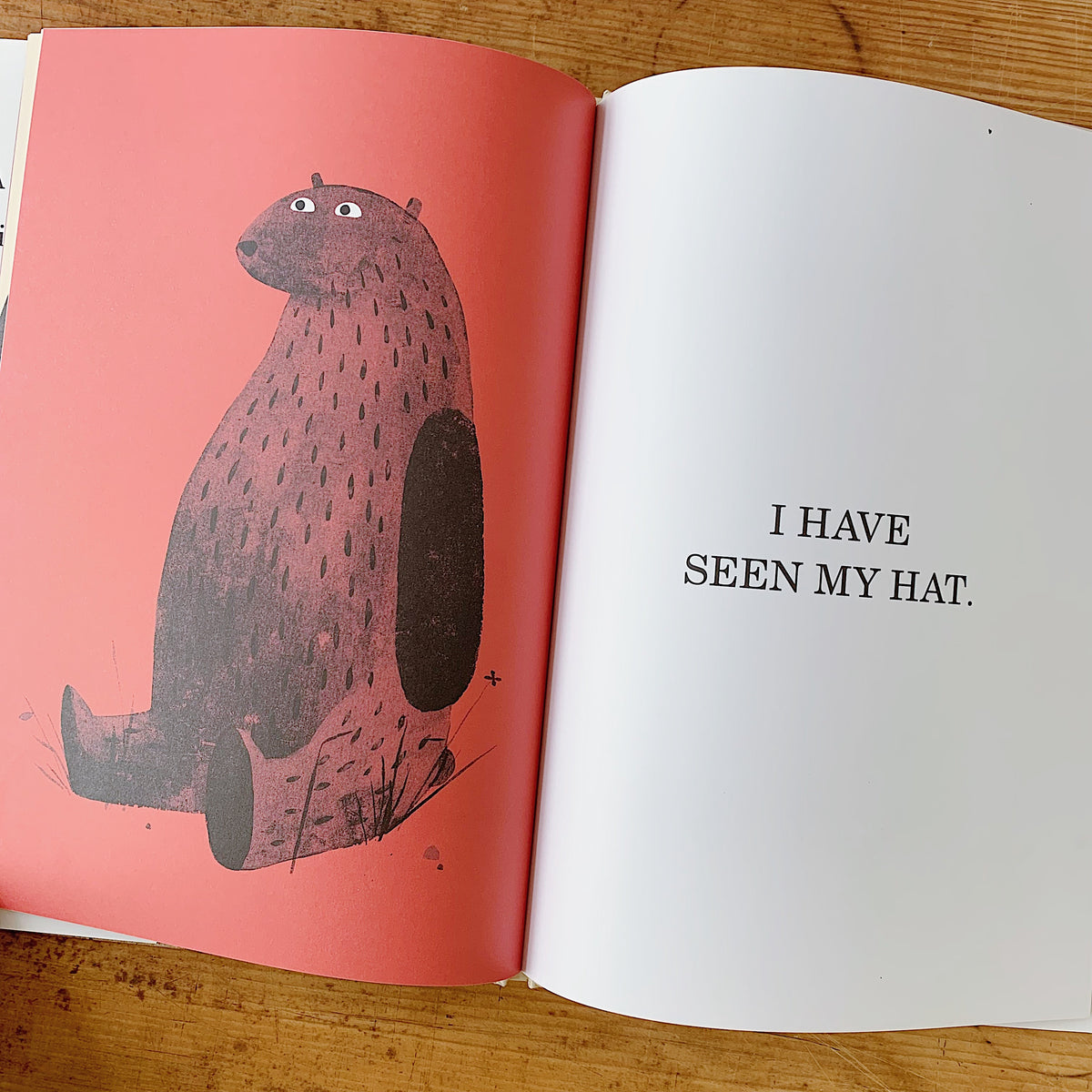 Interior spread of I Want My Hat Back showing the bear sitting upright against a coral-pink background, beside bold text reading "I HAVE SEEN MY HAT."
