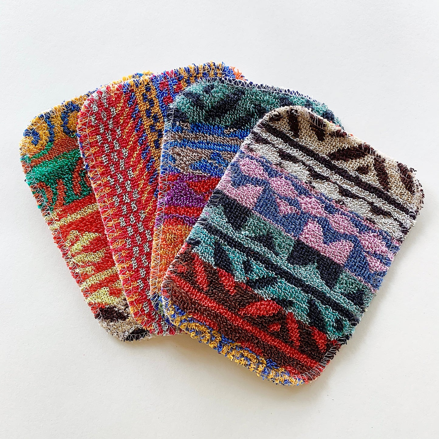 Top view of four colorful scrubby pad sponges splayed out on top of each other. 