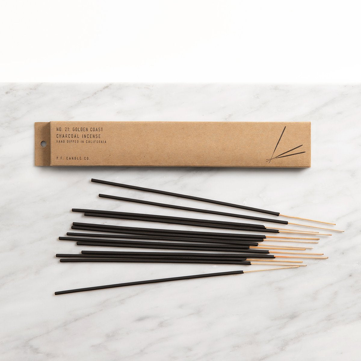 Golden coast incense lying flat next to its kraft package.