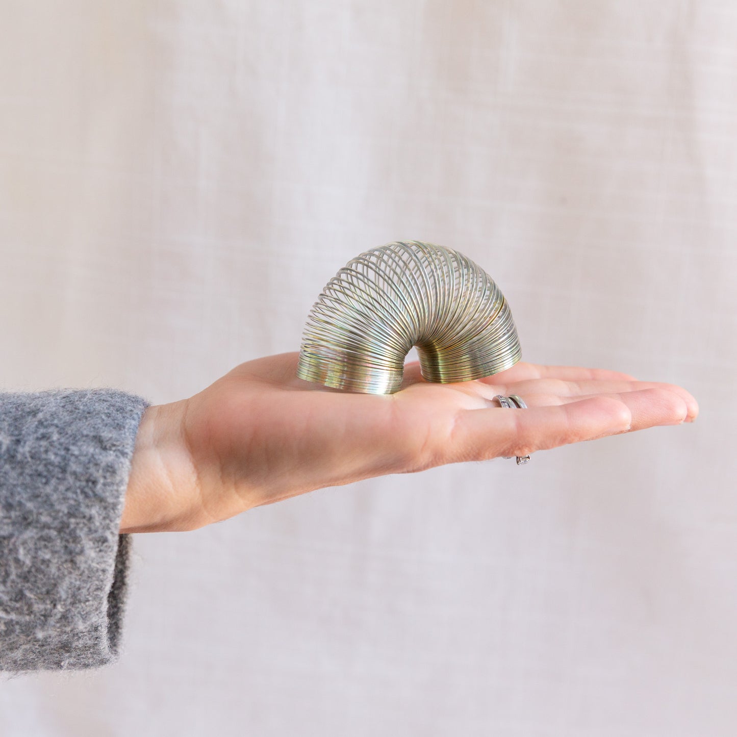diagonal view of mini slinky toy in hand for scale