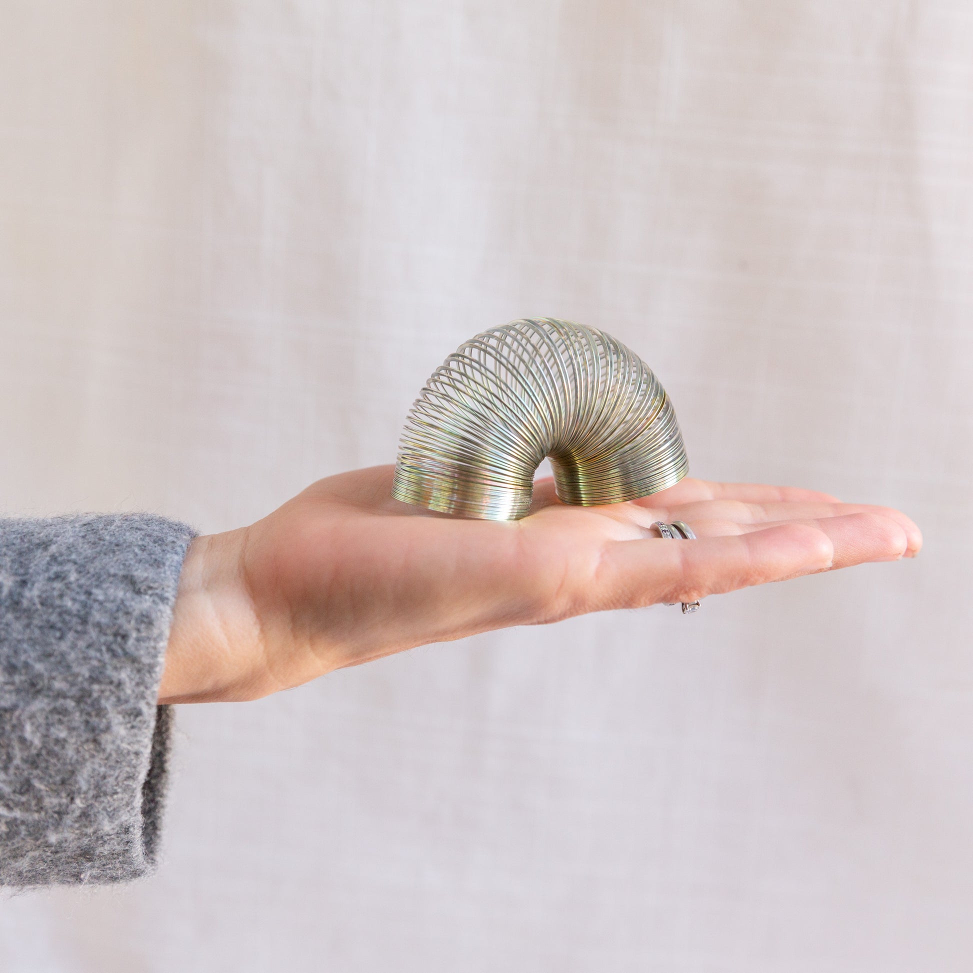 diagonal view of mini slinky toy in hand for scale