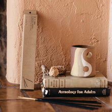 Load image into Gallery viewer, Pinon incense resting next to a stack of books and ceramic mug.
